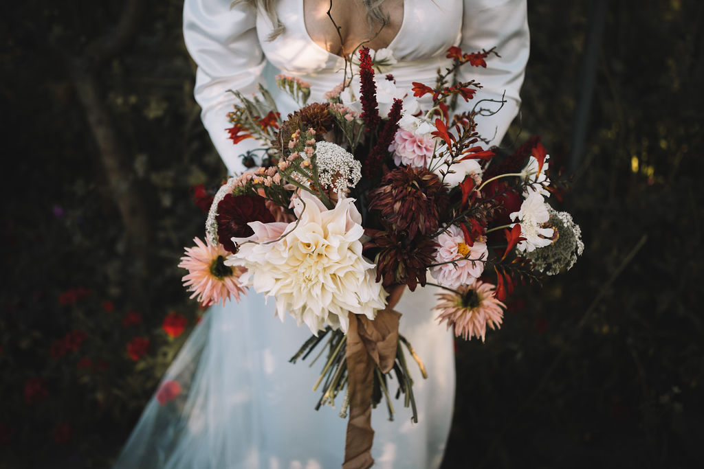 Gorgeous wedding bouquet in reds and pinks, photographed during an Edinburgh wedding at the secret herb garden.