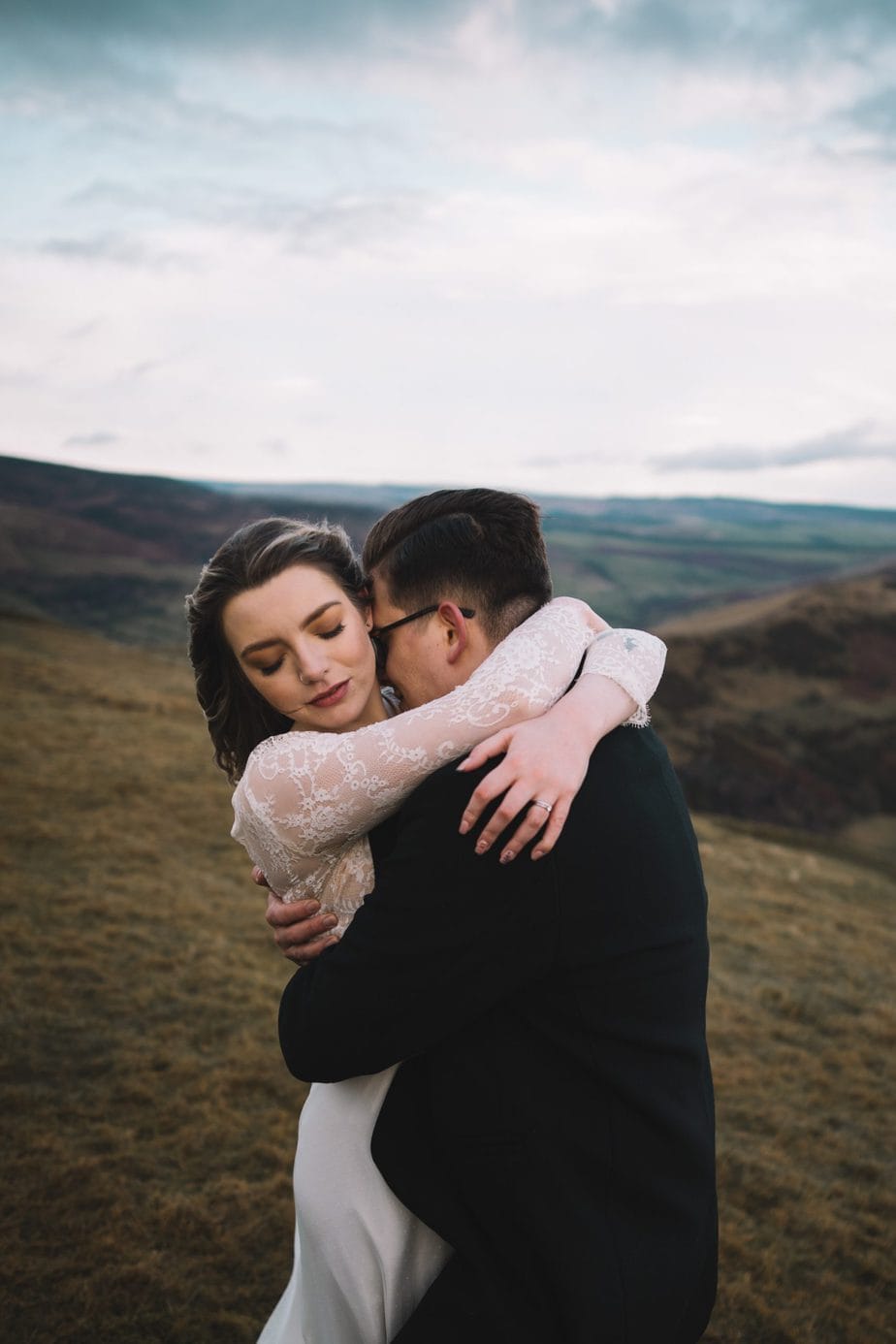 Bride and groom cuddling in the hills during their elopement.