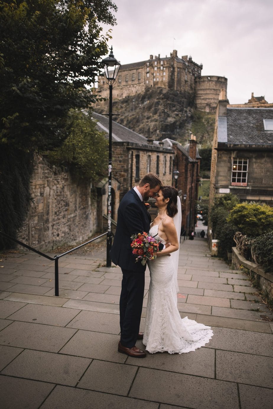 Bride and groom stood closely gazing at each other in front of Edinburgh castle during their Edinburgh elopement.