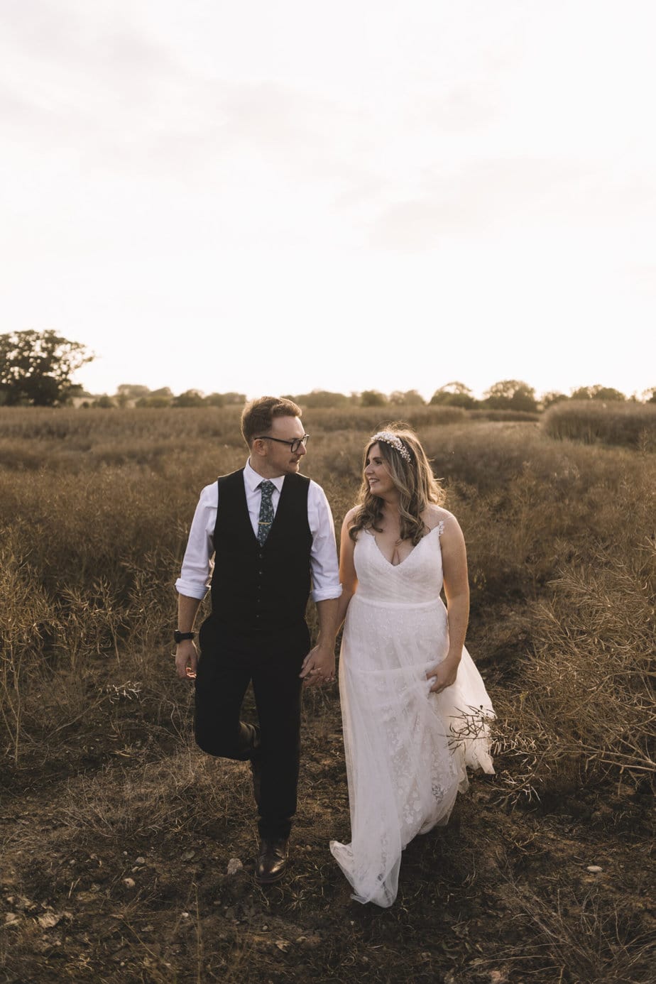 bride at sunset in gorgeous lace wedding dress. Smiling to camera with tipi and the Peak District in the background.