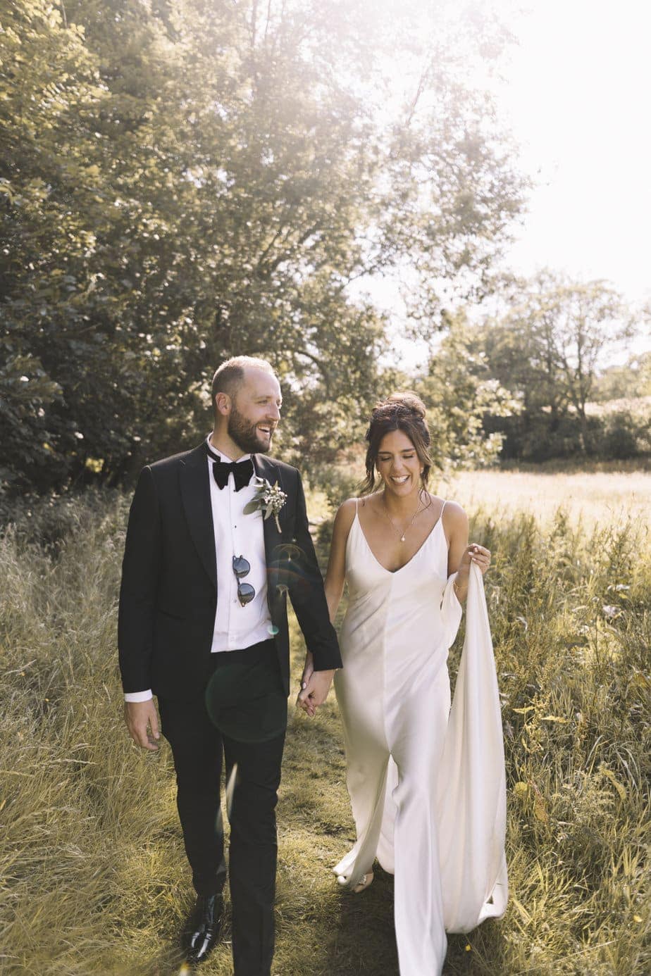 Stylish bride and groom holding hands in a field at The Venue Bowers Mill Halifax