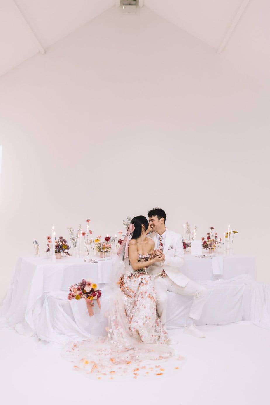 Five four studios manchester wedding venue, colourful table set up in white studio 1 with bride and groom kissing