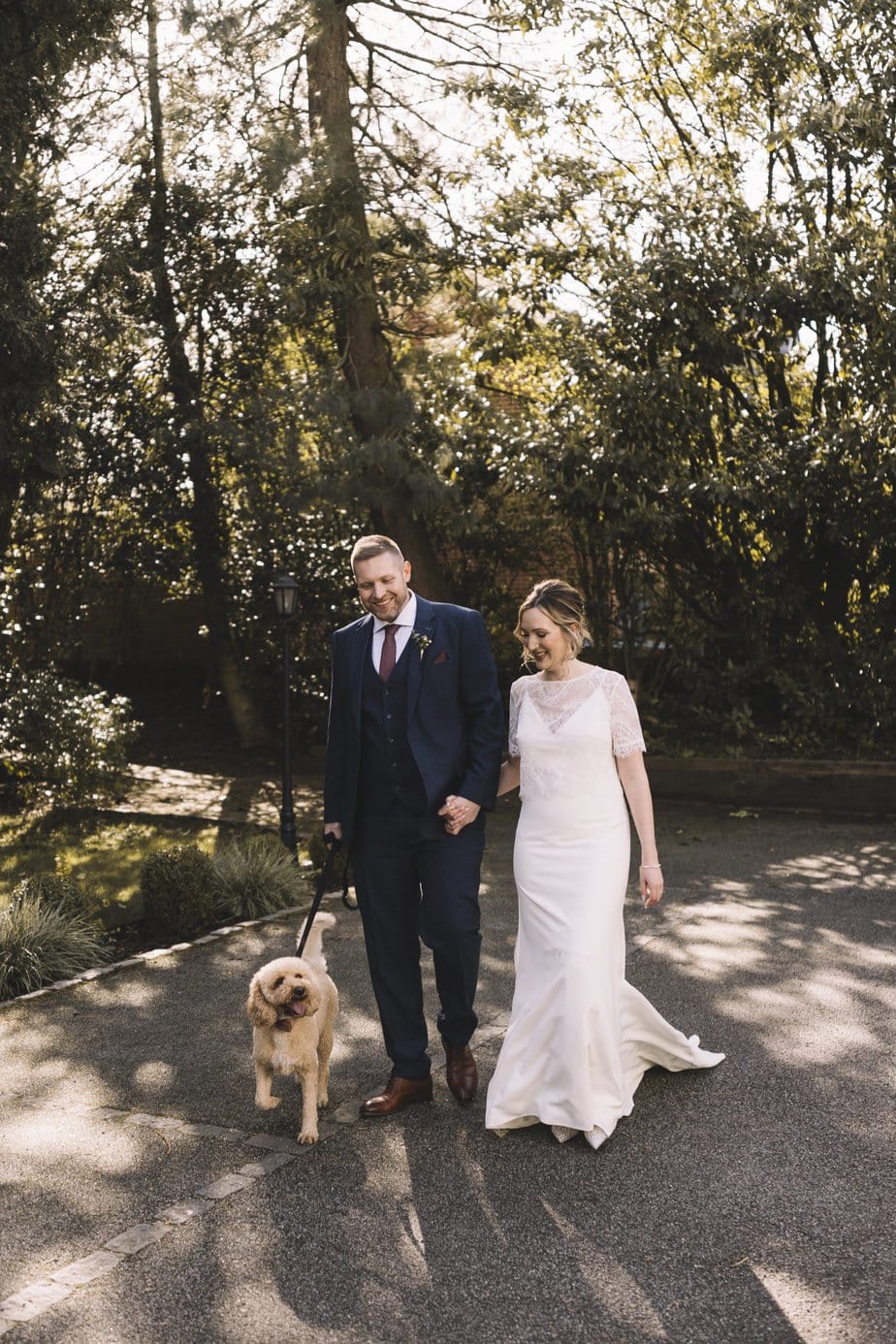 Bride and groom and their dog walking around the gardens of Didsbury house hotel