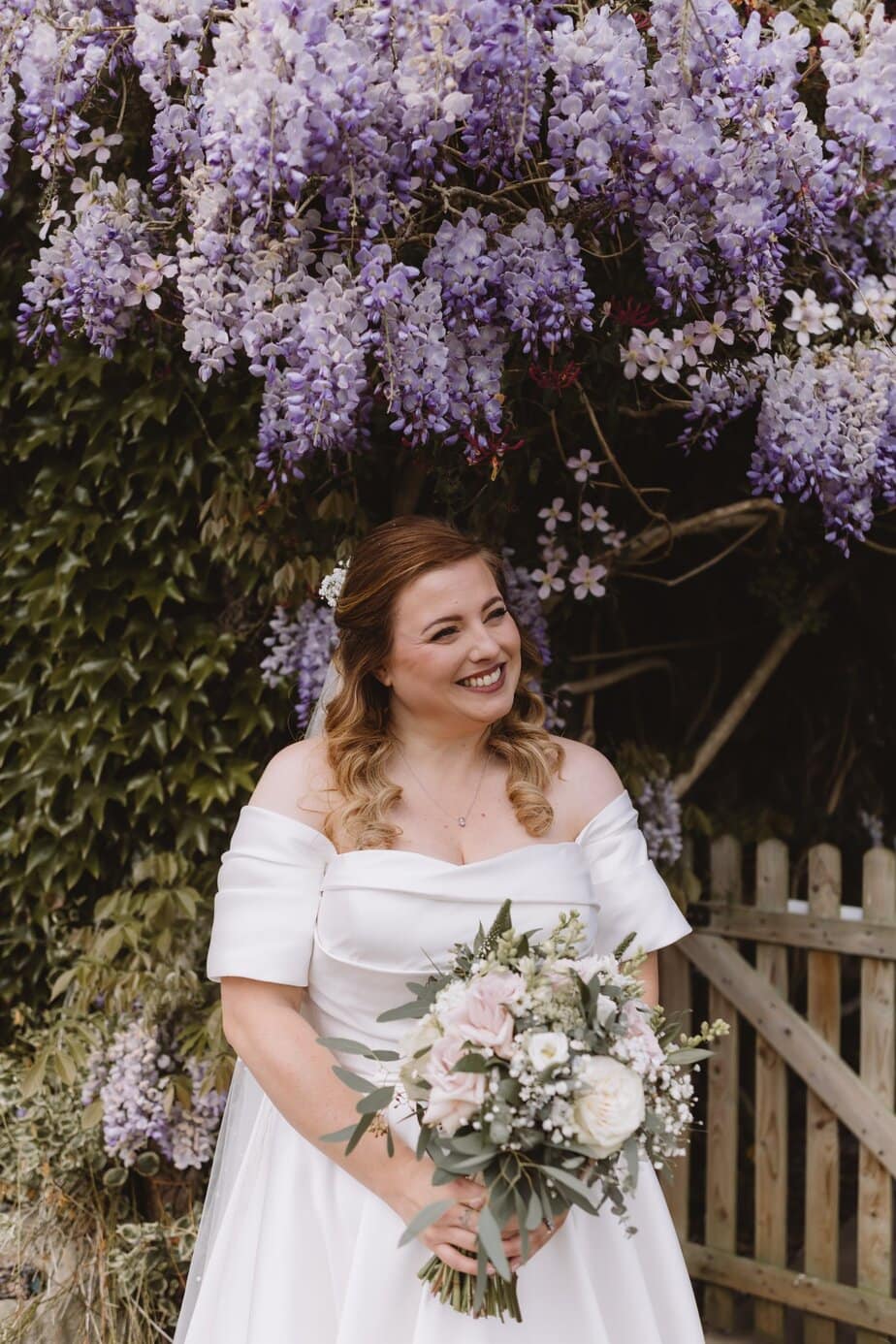 bride at sunset in gorgeous lace wedding dress. Smiling to camera with tipi and the Peak District in the background.